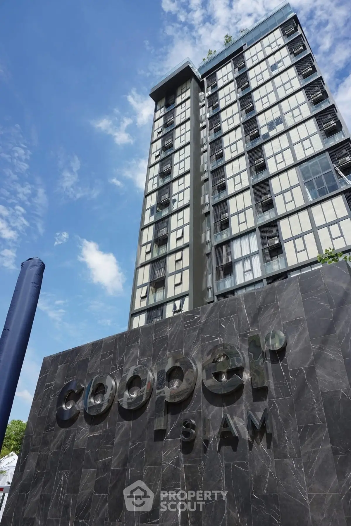 Modern high-rise building with sleek facade and clear blue sky backdrop.