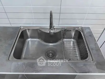 Modern stainless steel kitchen sink with sleek faucet in contemporary setting.