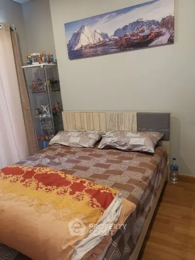 Cozy bedroom with stylish decor and mountain artwork, featuring a comfortable bed and display cabinet.
