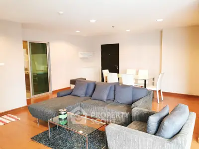 Spacious modern living room with stylish gray sofa and dining area in open layout apartment.