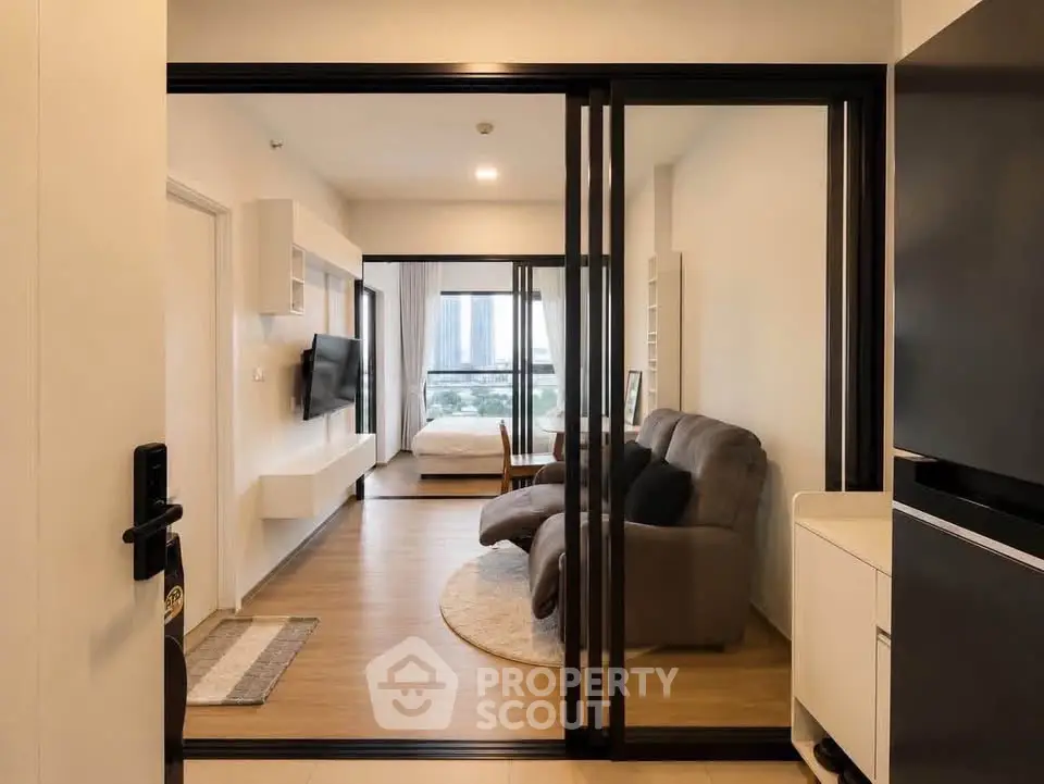 Modern apartment interior with sliding glass doors, cozy living area, and city view from the bedroom.