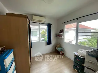 Cozy small room with wooden flooring and ample natural light from large windows.