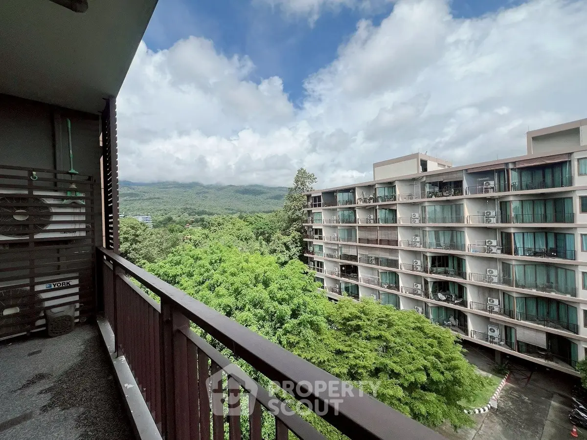 Stunning balcony view of lush greenery and modern apartment complex under a bright blue sky.