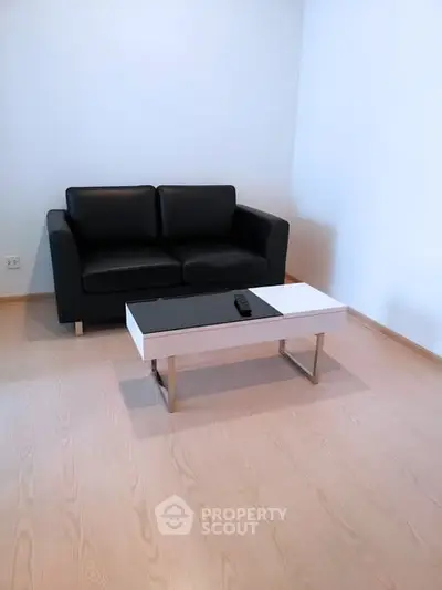 Modern minimalist living room with sleek black sofa and stylish coffee table.