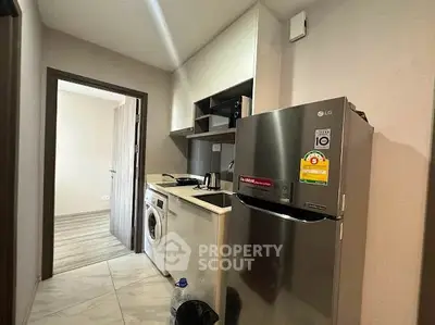 Modern kitchen with stainless steel fridge and washing machine in compact layout.