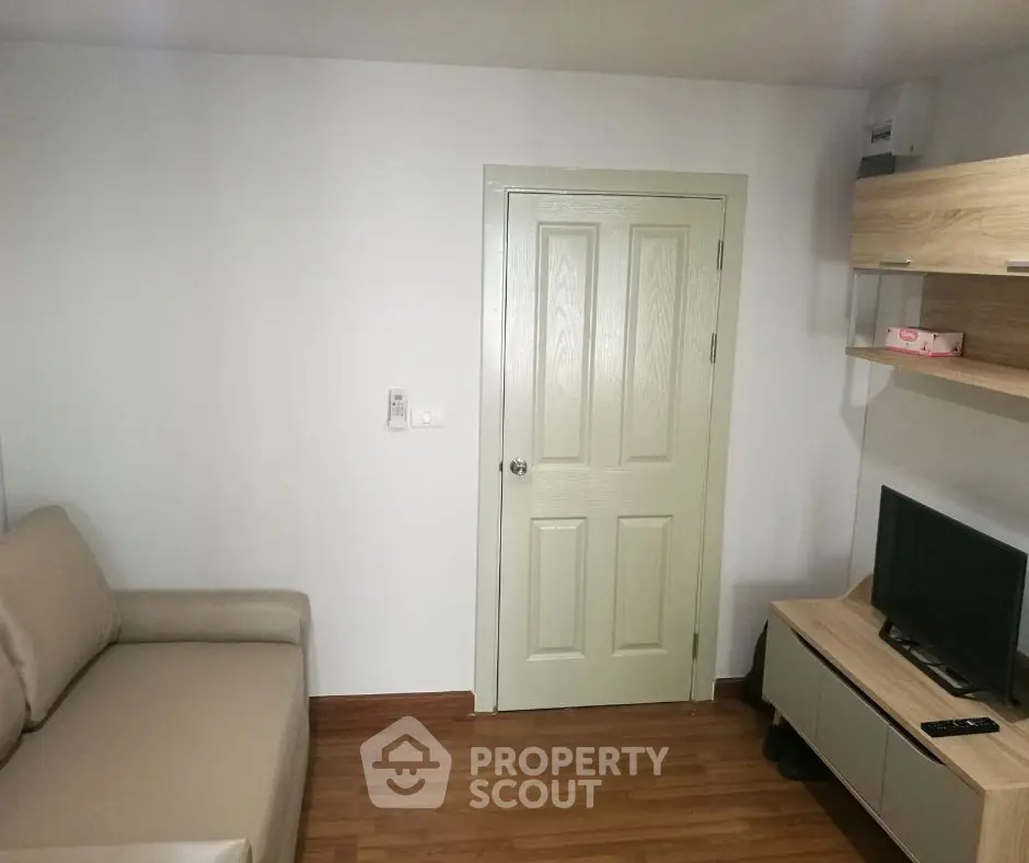 Cozy living room with beige sofa, wall-mounted TV, and wooden flooring for modern comfort.