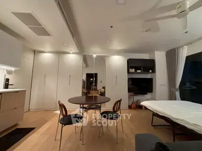 Modern living room with sleek furniture and open layout, featuring a round dining table and stylish chairs.