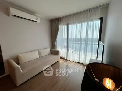 Modern living room with large window and cozy sofa, featuring elegant curtains and wooden flooring.