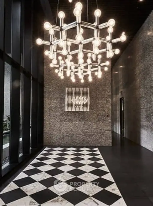 Luxurious building entrance with modern chandelier and elegant checkered flooring.