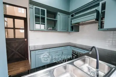 Elegant kitchen with teal cabinets and modern appliances in a stylish home