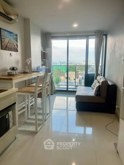Modern living room with balcony and city view, featuring sleek furniture and natural light.