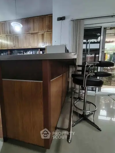 Modern kitchen with sleek bar stools and wooden cabinetry, featuring a stylish open layout.
