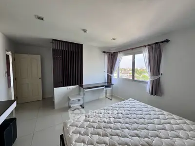 Spacious bedroom with large window offering city views, featuring modern decor and ample natural light.