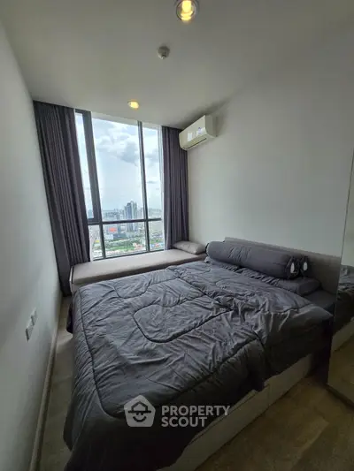 Modern bedroom with city view and large window, featuring cozy bedding and air conditioning.