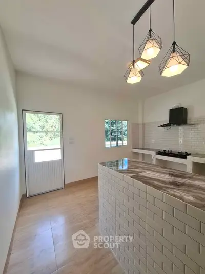 Modern kitchen with stylish lighting and gas stove, featuring a sleek open layout and natural light.