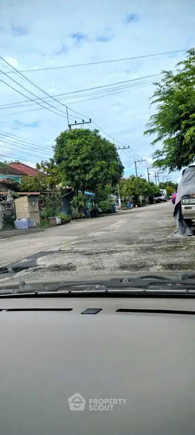 Charming suburban street view with lush greenery and parked cars, perfect for tranquil living.