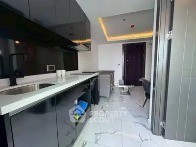 Modern kitchen with sleek black cabinets and open layout leading to a stylish living area.