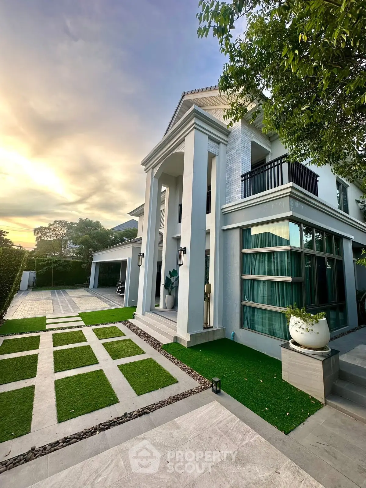 Stunning modern house with elegant facade and lush garden at sunset.