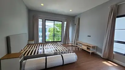 Spacious bedroom with large windows and wooden flooring, ready for furnishing.