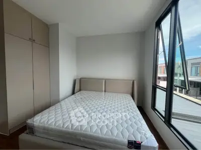 Modern bedroom with large windows and built-in wardrobe, offering natural light and contemporary design.