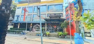 Charming street view of a vibrant commercial building with lush greenery and colorful facade.