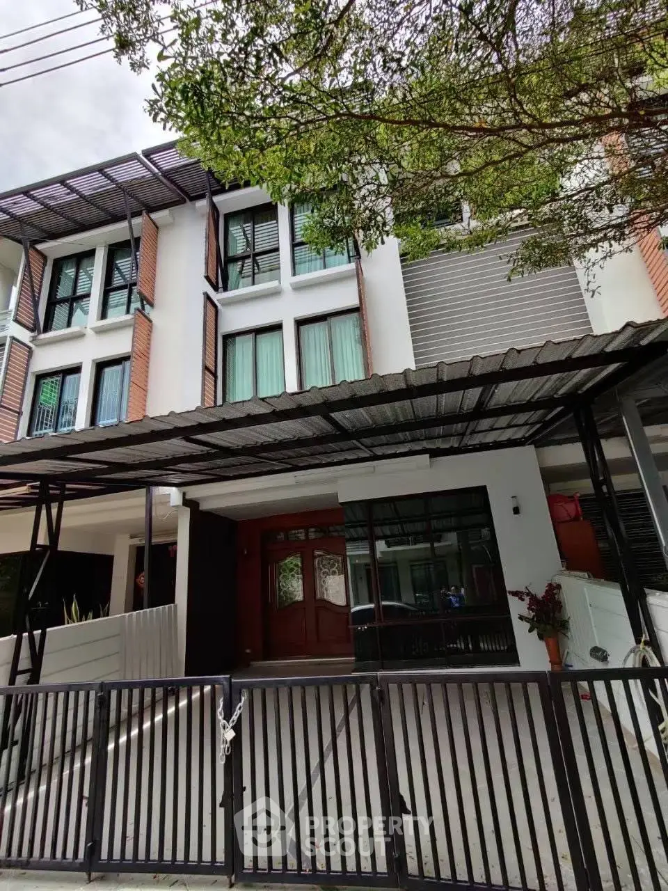 Modern townhouse exterior with gated entrance and lush greenery.