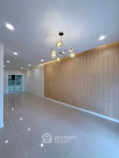 Spacious modern living room with elegant lighting and wood accent wall, perfect for stylish living.