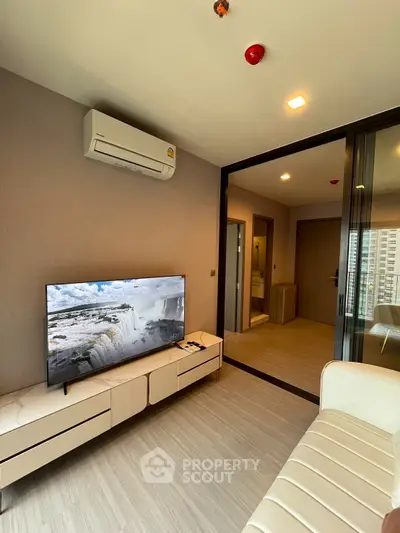 Modern living room with sleek design and large TV, featuring air conditioning and stylish furniture.