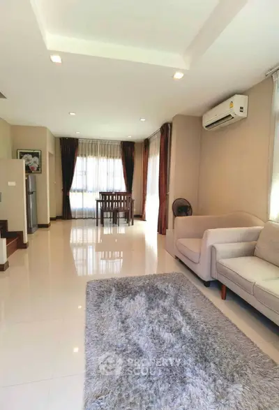 Spacious living room with modern decor and natural light, featuring a cozy sofa and dining area.