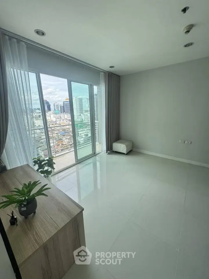 Spacious living room with large windows offering stunning city views and modern decor.