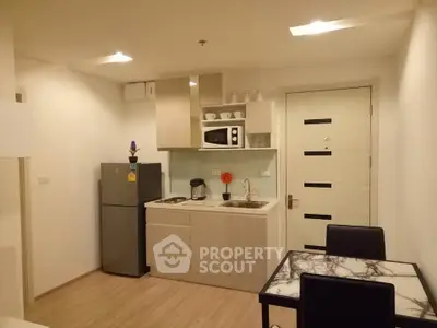 Modern kitchen with sleek appliances and dining area in stylish apartment.