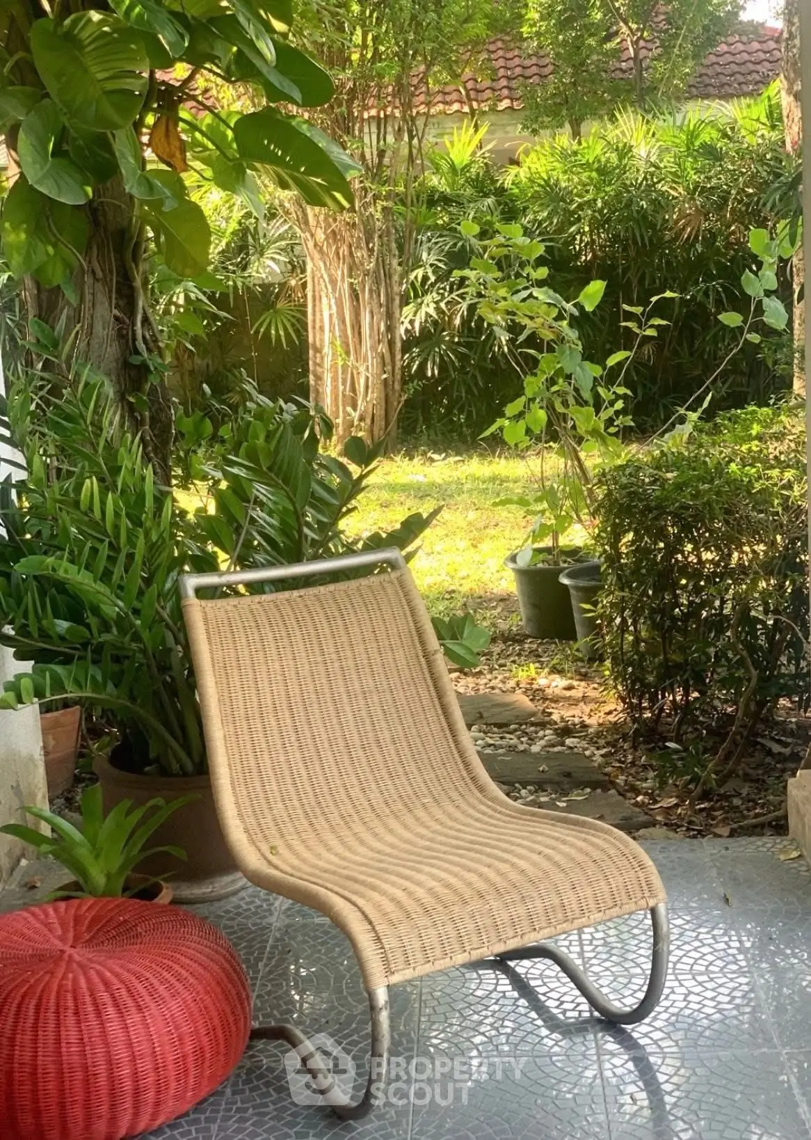 Charming garden patio with wicker chair and lush greenery, perfect for relaxation and outdoor enjoyment.