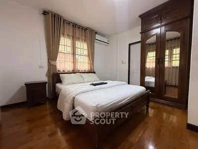Cozy bedroom with wooden flooring and mirrored wardrobe