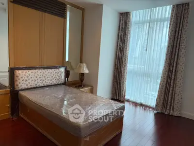 Spacious bedroom with large window and elegant curtains in modern apartment.