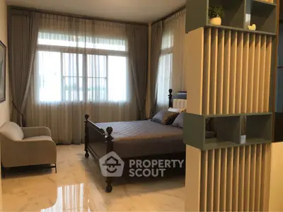 Luxurious bedroom with elegant decor and large windows offering natural light.