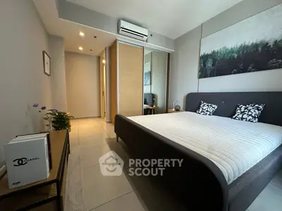 Modern bedroom with stylish decor and mirrored wardrobe, featuring a cozy bed and elegant artwork.
