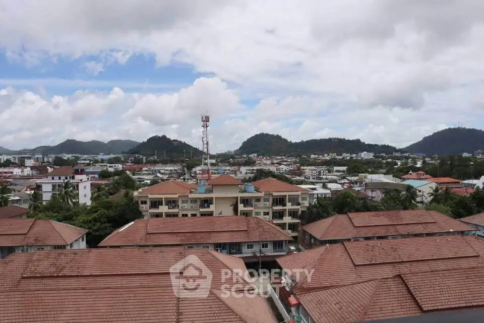 Scenic aerial view of residential area with mountains in the background, showcasing red-roofed buildings.