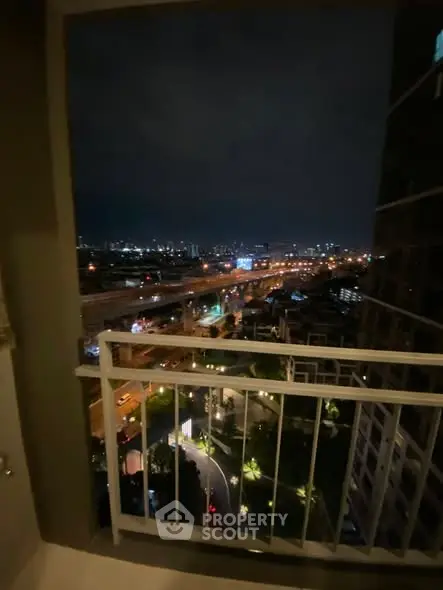 Stunning cityscape view from a high-rise balcony at night, showcasing vibrant urban lights.