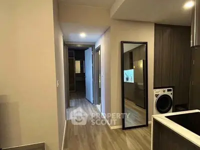 Modern apartment hallway with wooden flooring and sleek kitchen design