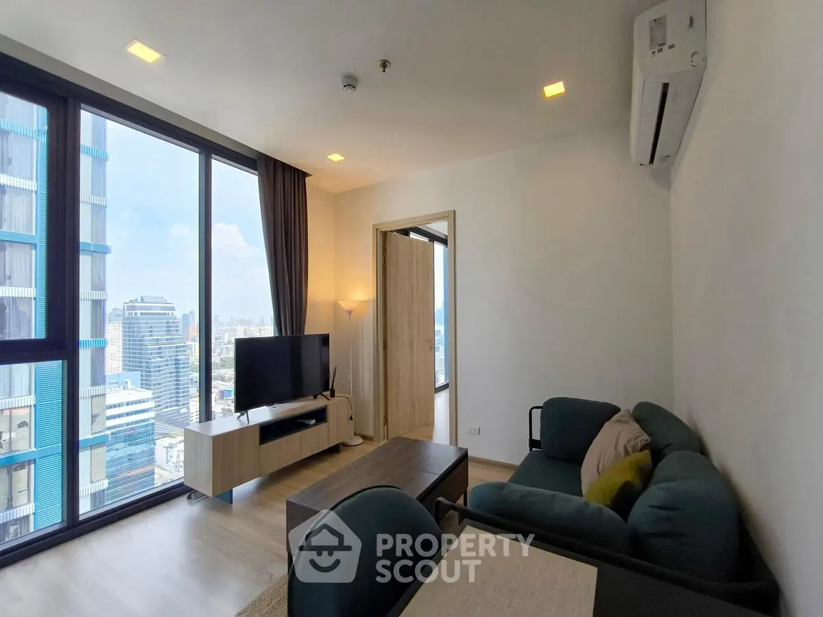 Modern living room with city view, featuring sleek furniture and large windows for natural light.