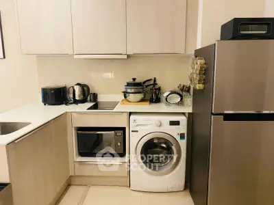 Modern kitchen with sleek appliances including washing machine and microwave.