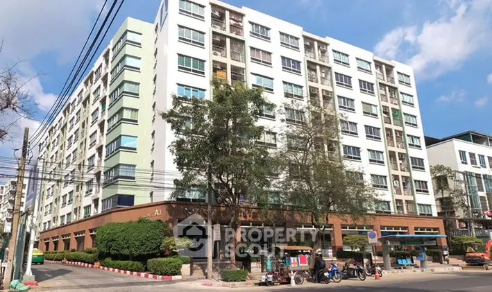 Modern multi-story apartment building with lush greenery and clear blue sky.
