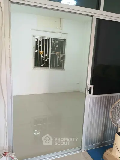 Spacious empty room with sliding glass door and decorative window grille