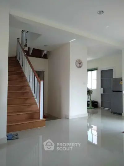 Spacious modern interior with wooden staircase and sleek kitchen area.