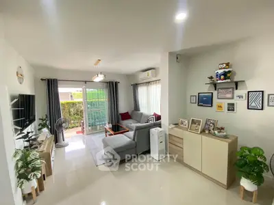 Spacious living room with modern decor and natural light, featuring a cozy seating area and stylish furnishings.