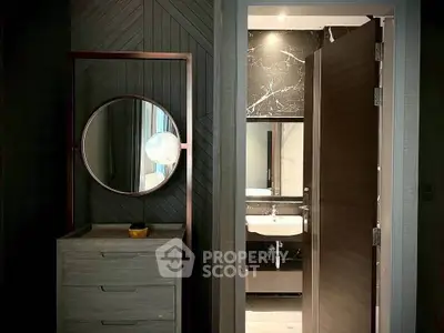 Modern bathroom with stylish vanity and round mirror, featuring elegant dark wood accents.
