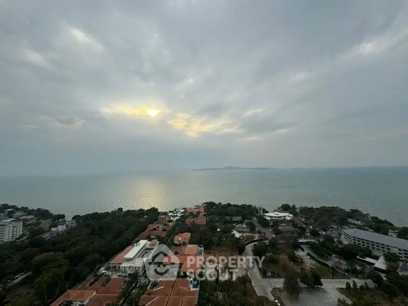 Stunning ocean view from high-rise building overlooking lush greenery and rooftops.
