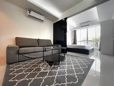 Modern living room with sleek sofa and stylish rug in open layout apartment.