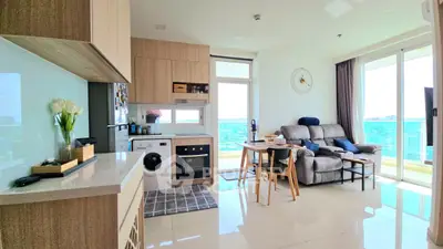 Modern living room with open kitchen, featuring sleek appliances and a cozy seating area with a view.