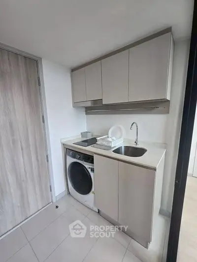 Modern compact kitchen with integrated washing machine and sleek cabinetry